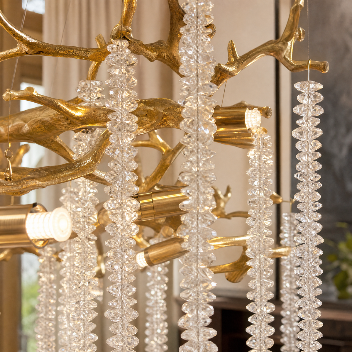 A Trivellolab gold metal branch chandelier with cascading crystal beads suspended in a rainfall arrangement.